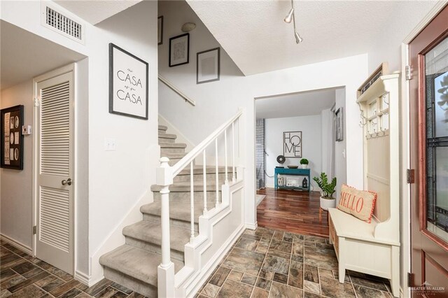 2405 E Lazy Lake Dr, Harlingen, TX 78550 - staircase with rail lighting, a textured ceiling, and baseboards