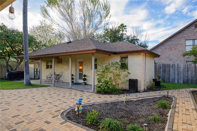 2405 E Lazy Lake Dr, Harlingen, TX 78550 - rear view of house with brick siding, a patio, and roof with shingles