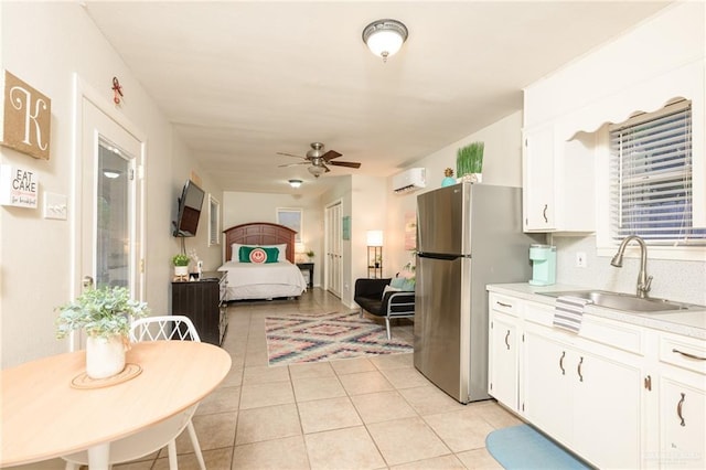 2405 E Lazy Lake Dr, Harlingen, TX 78550 - kitchen with a sink, freestanding refrigerator, a ceiling fan, light tile patterned floors, and white cabinetry