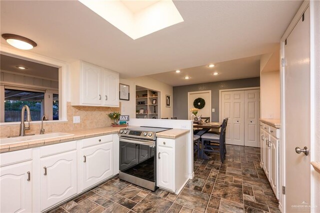 2405 E Lazy Lake Dr, Harlingen, TX 78550 - kitchen with stainless steel electric stove, a sink, white cabinetry, a peninsula, and recessed lighting
