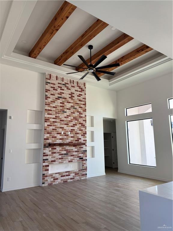 unfurnished living room featuring beam ceiling, hardwood / wood-style flooring, and ceiling fan