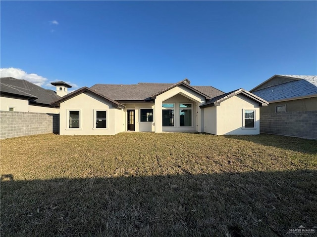 rear view of property featuring a lawn