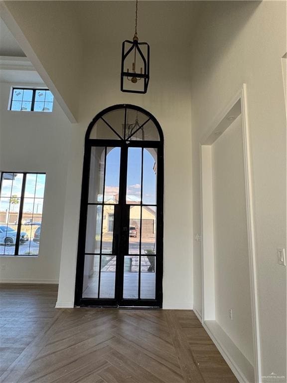 doorway with dark parquet flooring, plenty of natural light, french doors, and a notable chandelier