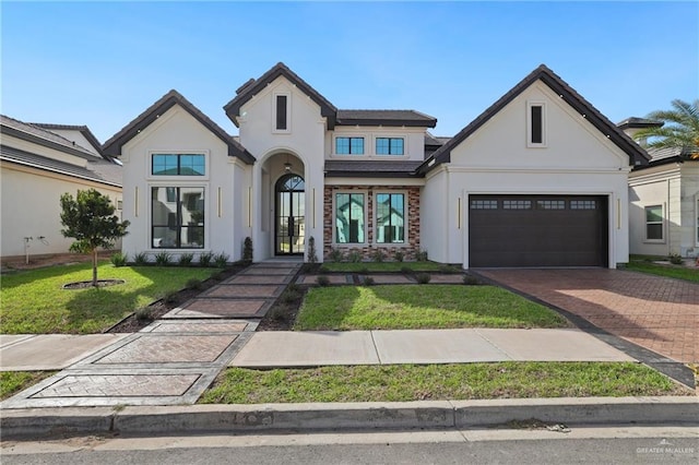 view of front of home featuring stucco siding, a front lawn, decorative driveway, french doors, and a garage