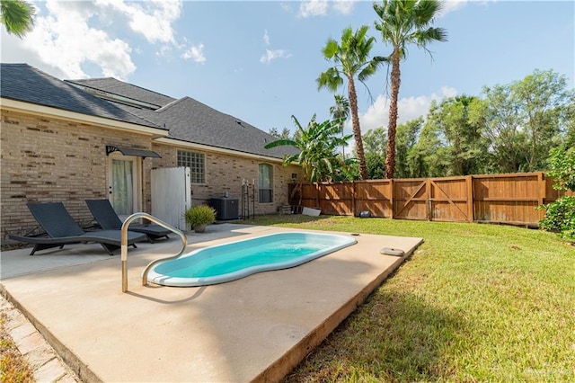 view of pool with a lawn, a patio, and central AC unit