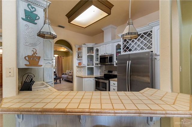 kitchen with pendant lighting, white cabinets, a kitchen breakfast bar, appliances with stainless steel finishes, and kitchen peninsula