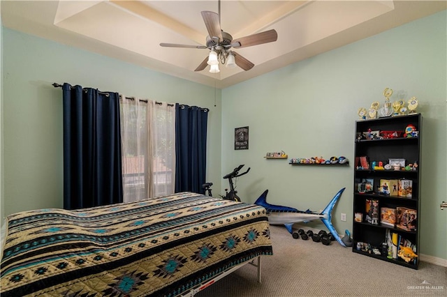 carpeted bedroom featuring a raised ceiling and ceiling fan