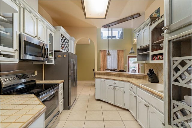 kitchen with tile countertops, white cabinetry, pendant lighting, and stainless steel appliances