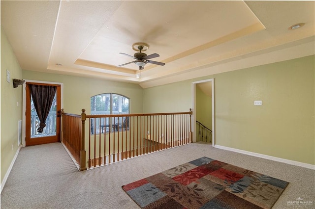 hallway featuring a tray ceiling and light carpet