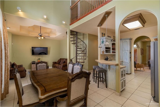 tiled dining room with a tray ceiling and ceiling fan