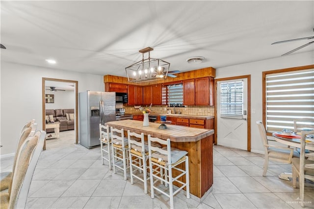 18064 Garrett Rd, Harlingen, TX 78552 - kitchen featuring appliances with stainless steel finishes, a ceiling fan, light tile patterned floors, tasteful backsplash, and brown cabinetry