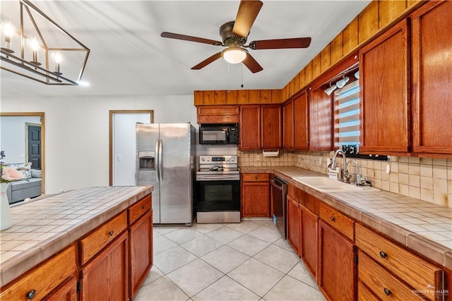 18064 Garrett Rd, Harlingen, TX 78552 - kitchen with stainless steel appliances, tile counters, backsplash, and brown cabinets