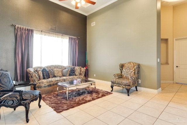 tiled living room featuring a high ceiling, ceiling fan, and ornamental molding