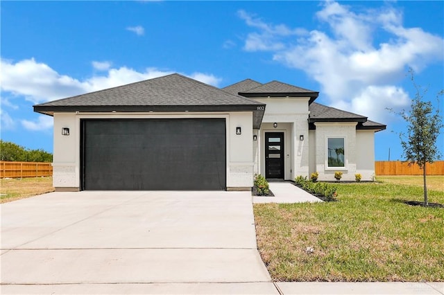 prairie-style house with stucco siding, concrete driveway, an attached garage, and fence