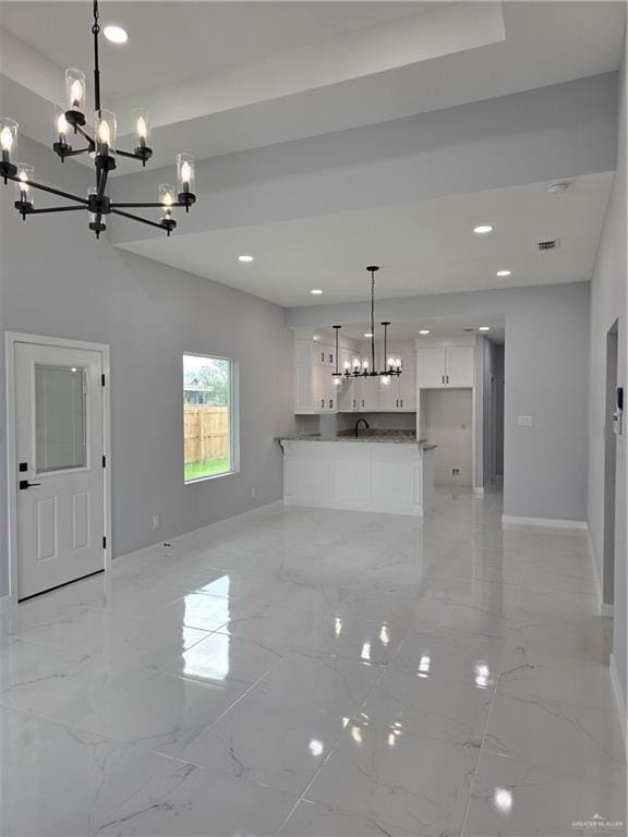 unfurnished living room featuring sink and an inviting chandelier