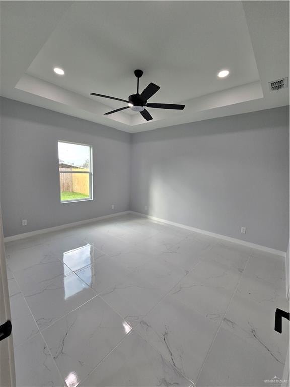 spare room with a raised ceiling and ceiling fan