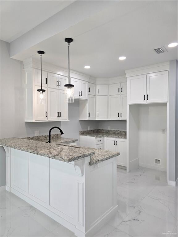 kitchen featuring kitchen peninsula, white cabinets, pendant lighting, and stone countertops