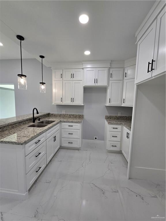 kitchen with white cabinets, pendant lighting, dark stone counters, and sink