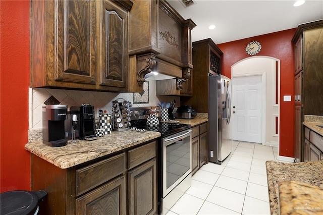 kitchen featuring decorative backsplash, light stone counters, light tile patterned floors, and stainless steel appliances