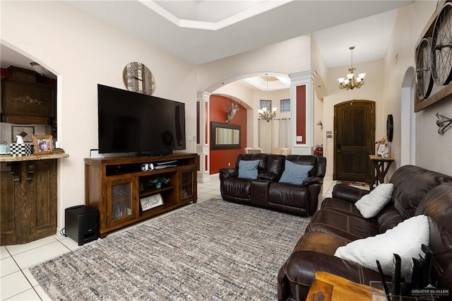 living room featuring decorative columns, light tile patterned floors, and a notable chandelier