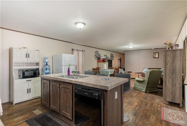 kitchen with an island with sink, a sink, black appliances, and dark wood finished floors