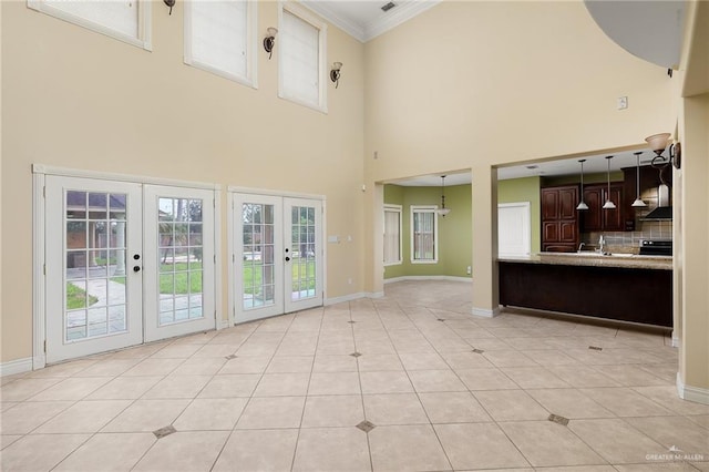 unfurnished living room with light tile patterned flooring, french doors, crown molding, and a high ceiling