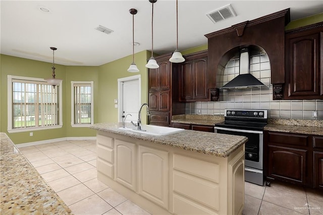 kitchen featuring pendant lighting, a center island with sink, sink, decorative backsplash, and stainless steel electric range oven