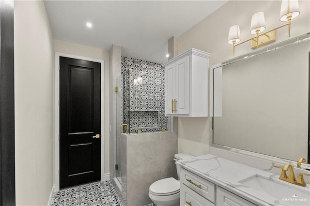 bathroom with vanity, a shower with shower door, tile walls, and toilet