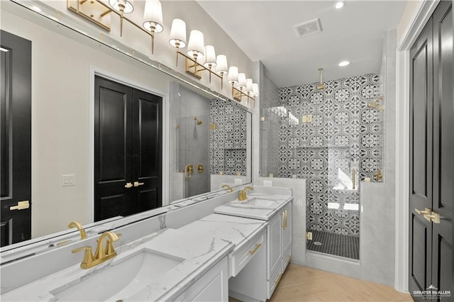 bathroom featuring parquet flooring, vanity, and tiled shower