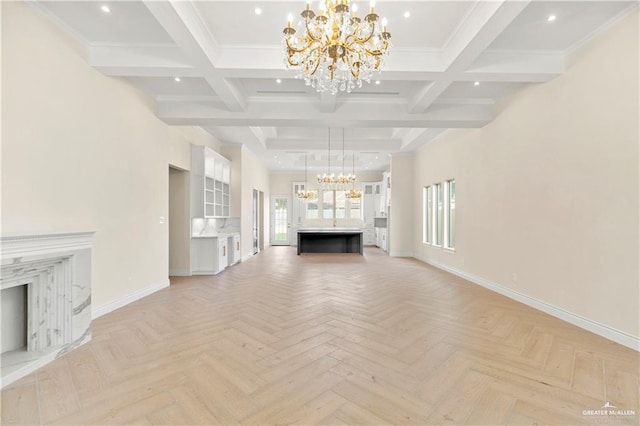 unfurnished living room featuring an inviting chandelier, ornamental molding, a high end fireplace, and light parquet floors