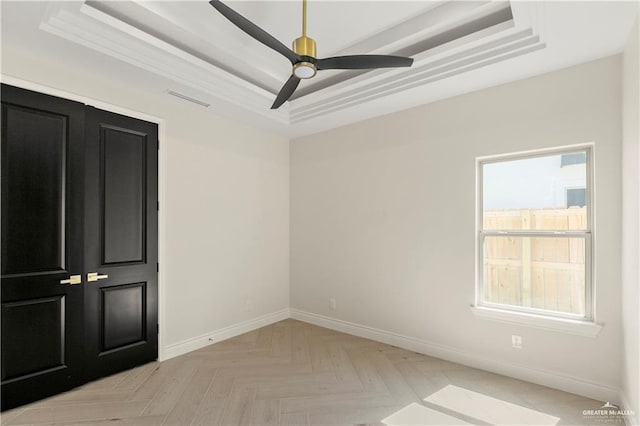 unfurnished room featuring ceiling fan, a raised ceiling, and light parquet floors