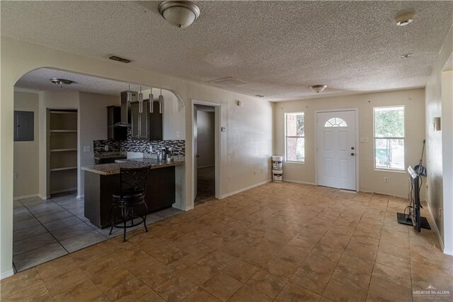 kitchen featuring a kitchen breakfast bar, kitchen peninsula, decorative backsplash, and a textured ceiling