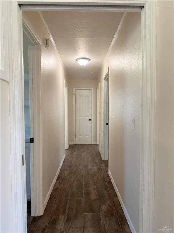 hallway with dark hardwood / wood-style floors and ornamental molding