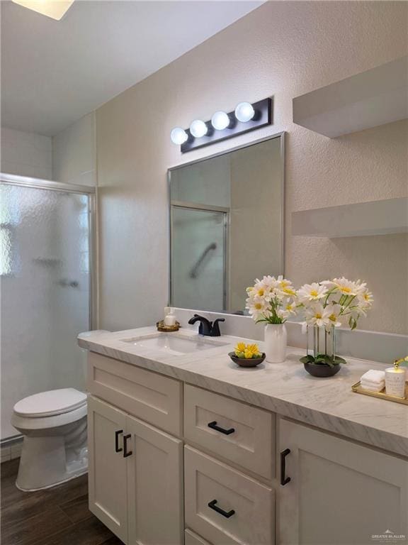 bathroom featuring hardwood / wood-style floors, vanity, toilet, and a shower with shower door