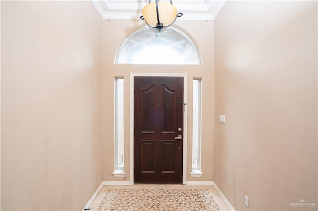 foyer featuring light tile patterned flooring, crown molding, and a high ceiling