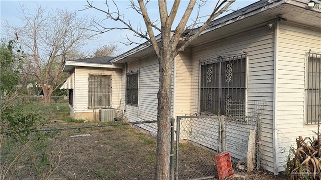 view of side of home featuring a gate, central air condition unit, and fence