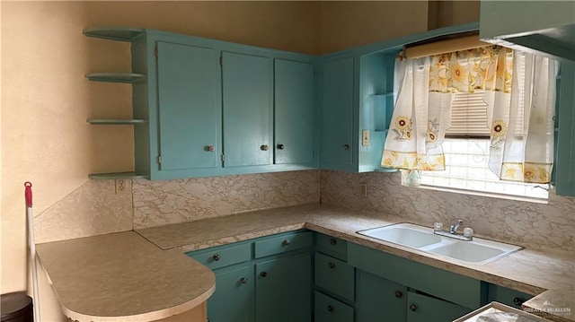 kitchen with open shelves, decorative backsplash, light countertops, and a sink