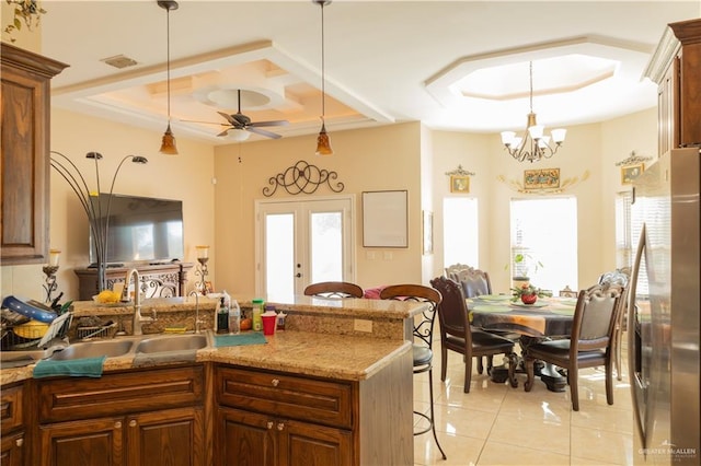 kitchen featuring a kitchen breakfast bar, stainless steel refrigerator with ice dispenser, french doors, decorative light fixtures, and sink