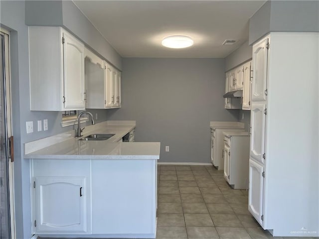 403 Gemini St, Mission, TX 78572 - kitchen featuring a sink, a peninsula, light countertops, under cabinet range hood, and white cabinets