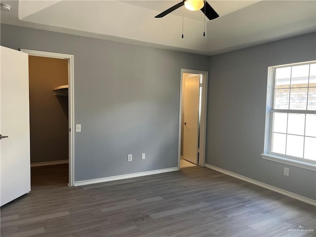 403 Gemini St, Mission, TX 78572 - unfurnished bedroom featuring a walk in closet, wood finished floors, baseboards, and a ceiling fan