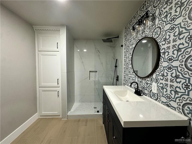 full bathroom featuring a marble finish shower, baseboards, wood finish floors, and vanity