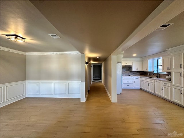 kitchen with visible vents, freestanding refrigerator, light wood-type flooring, white cabinetry, and a sink