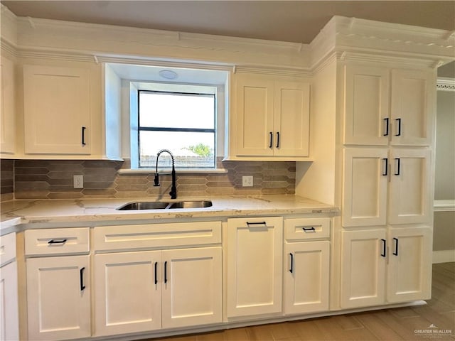 kitchen with white cabinetry, a sink, and light stone countertops