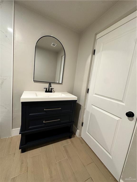 bathroom with wood tiled floor, visible vents, vanity, and baseboards