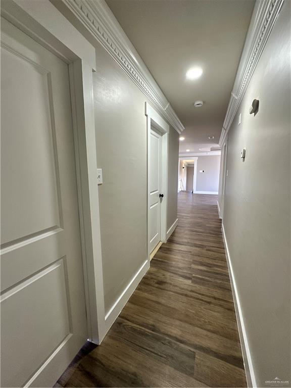 corridor with baseboards, ornamental molding, dark wood-type flooring, and recessed lighting