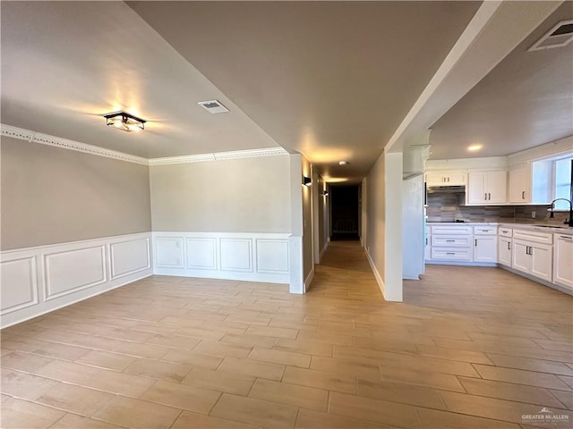 empty room with a wainscoted wall, a sink, and visible vents