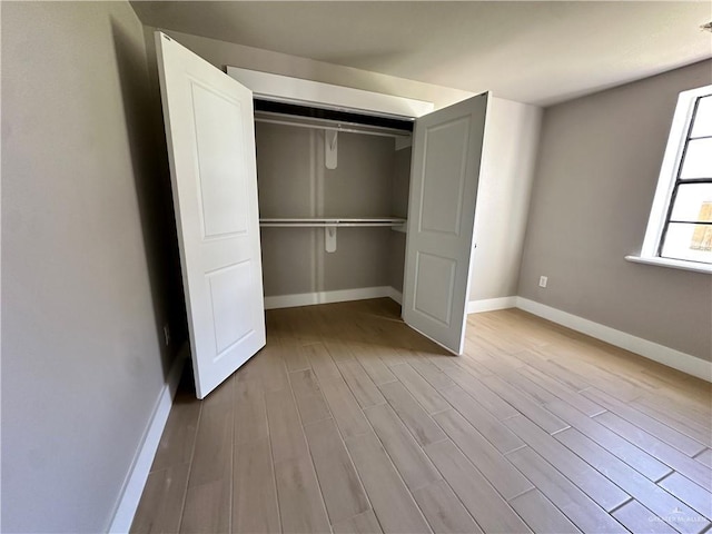 unfurnished bedroom with light wood-style floors, a closet, and baseboards