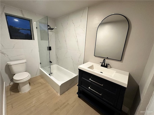 bathroom featuring toilet,  shower combination, wood tiled floor, vanity, and tile walls