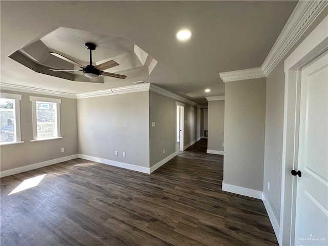 empty room featuring baseboards, dark wood-style floors, a raised ceiling, and crown molding