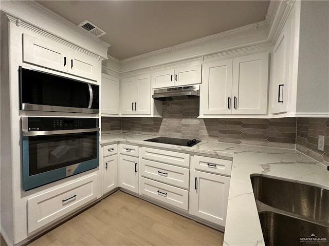 kitchen with oven, under cabinet range hood, visible vents, white cabinetry, and light stone countertops